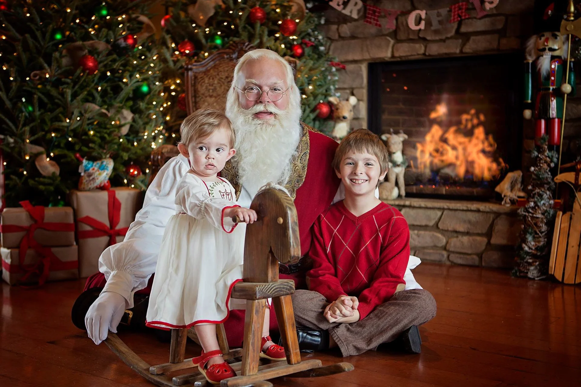 Sneaky Santa — Santa goes where the children are, sometimes that means the floor. Little girl on the rocking horse didn’t know he had slid into the shot! She loves Santa today, by the way. Photo courtesy of Blessed Reflection Photography.
