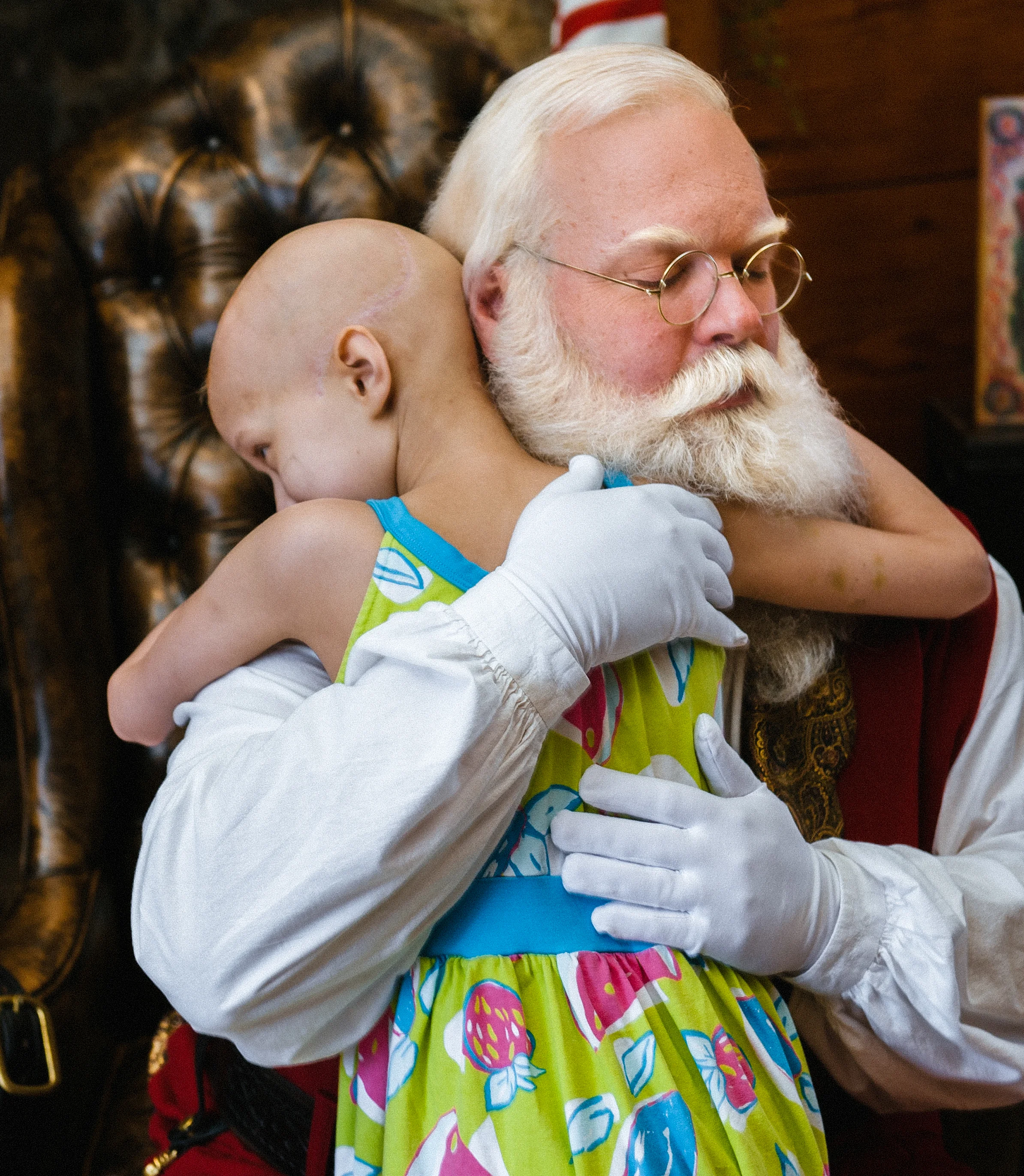 Precious hug! — This little girl, along with a lobby-full of others, spent Christmas in the hospital getting chemotherapy and basically missed Christmas. So a group of local charities and busniesses gave them a Christmas in July. Santa was thrilled to participate.